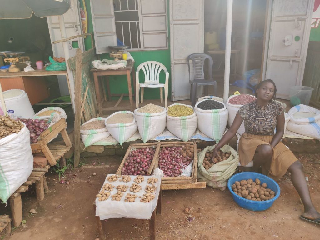 Bohnen in Säcken neben eine Frau in Uganda